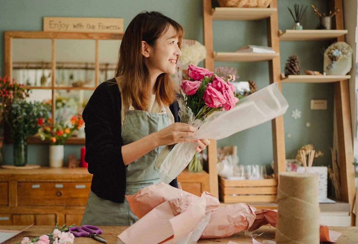 Florist hand-wrapping a bouquet of fresh roses